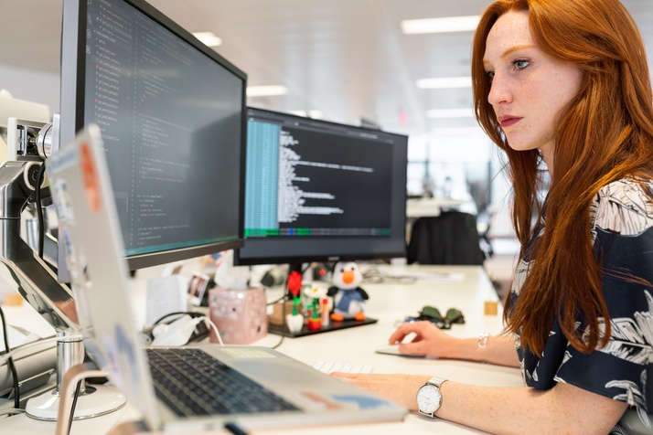 A lady works at a multi-monitor computer setup