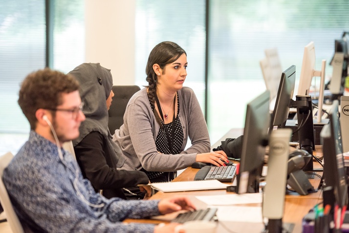 Three customer service representatives working at computers in a help center.