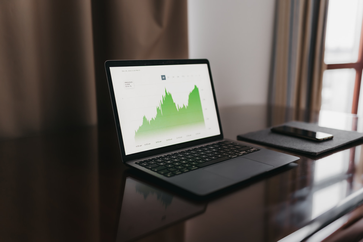 A laptop sat on a desk displaying a graph of metrics and data.